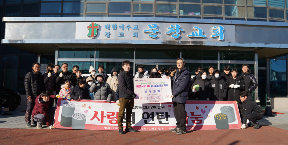 강국경(앞줄 왼쪽) 집사와 박진규 목사가 이웃사랑 연탄 기증식을 하고 관계자들과 기념 촬영을 하고 있다.